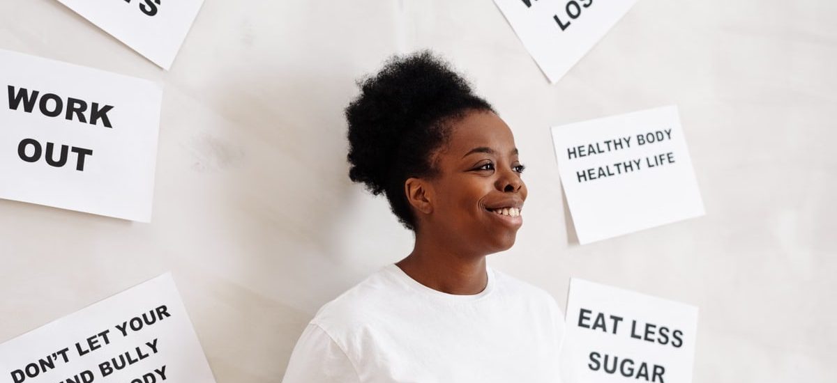 Portrait of a smiling woman surrounded by health motivation signs on a white background, promoting a healthy lifestyle.