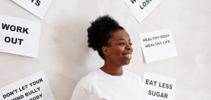 Portrait of a smiling woman surrounded by health motivation signs on a white background, promoting a healthy lifestyle.