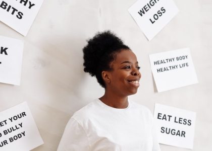 Portrait of a smiling woman surrounded by health motivation signs on a white background, promoting a healthy lifestyle.